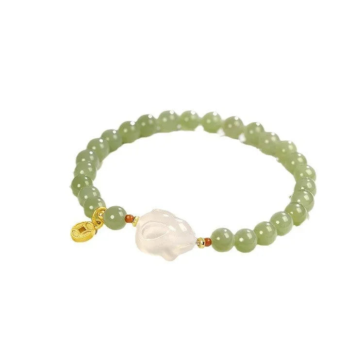 Close-up of a women's handmade bracelet with a detailed jade rabbit charm in a gift box.