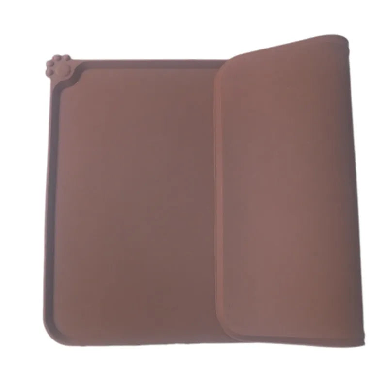Grey silicone pet food mat with raised edges on a tile floor