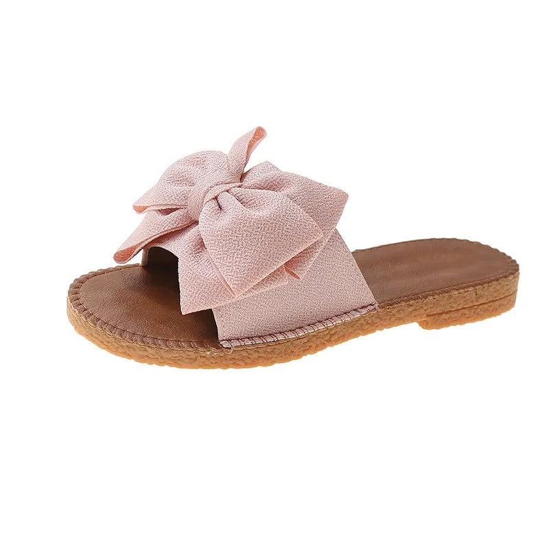 Women's beige suede slip-on sandals with bow detail and rubber sole