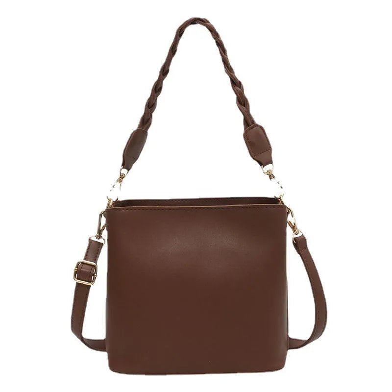 Khaki woven crossbody bucket bag with a buckle, shown on a model for scale