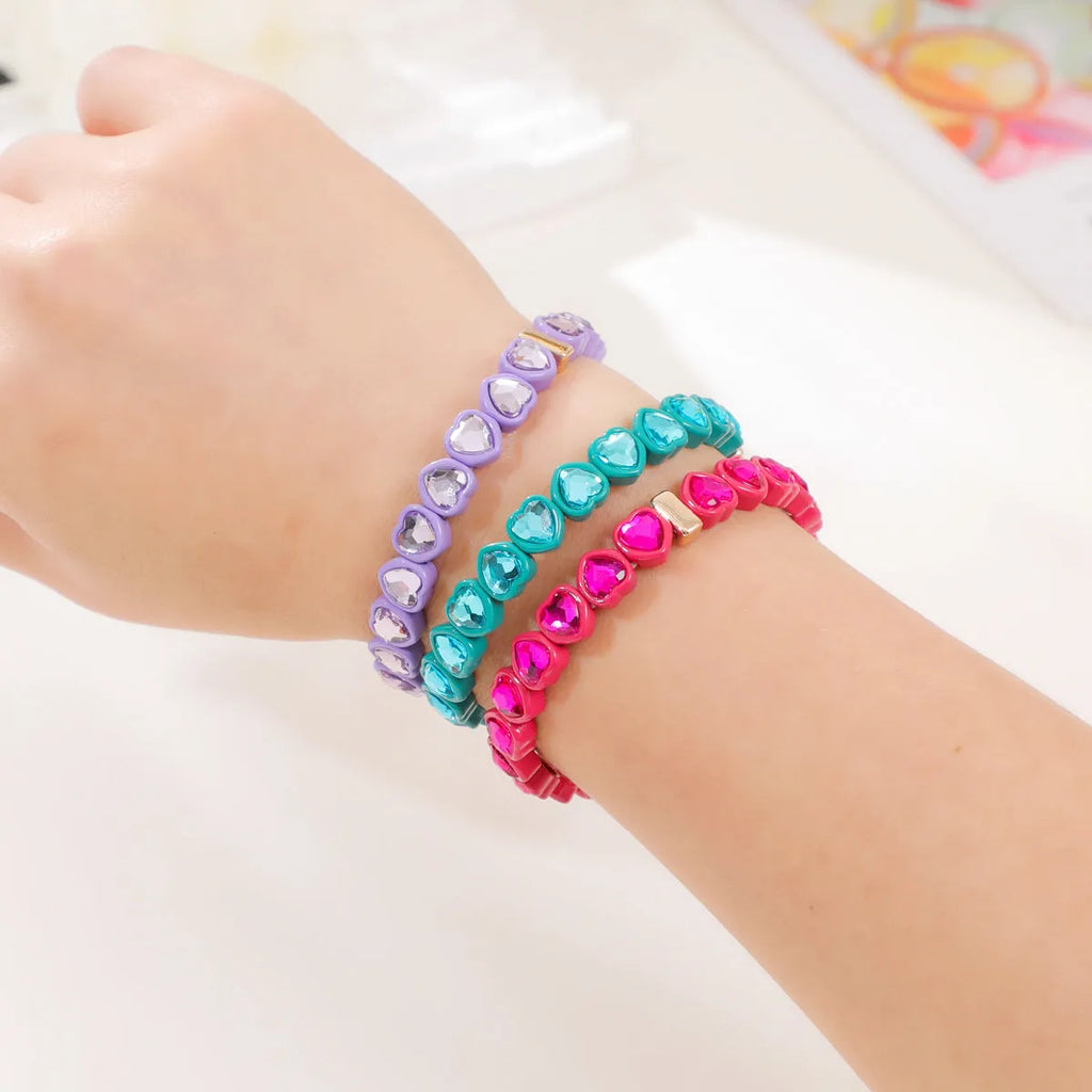 Colourful enamel heart-shaped stretch bracelet on a wrist showing the alloy and elastic band construction.