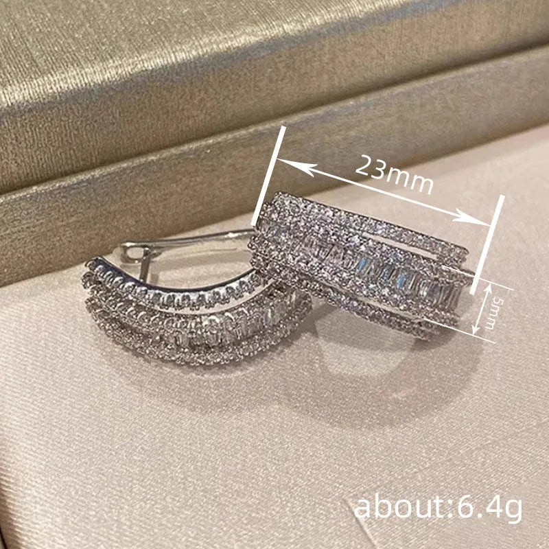 A pair of women's geometric stud earrings in white gold colour with a central inlaid zircon stone.