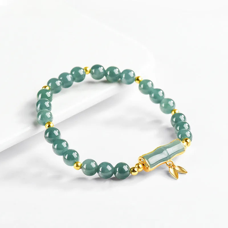 Simple sterling silver bracelet with a raised setting holding a natural blue jade round bead.