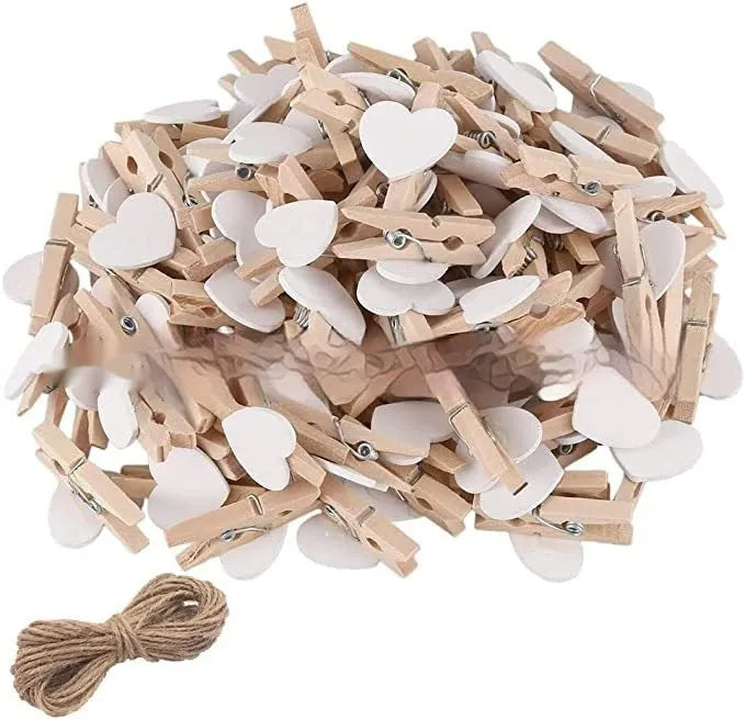 Five small wooden heart-shaped clips in red, pink, white, yellow, and rose colours on a wooden surface.