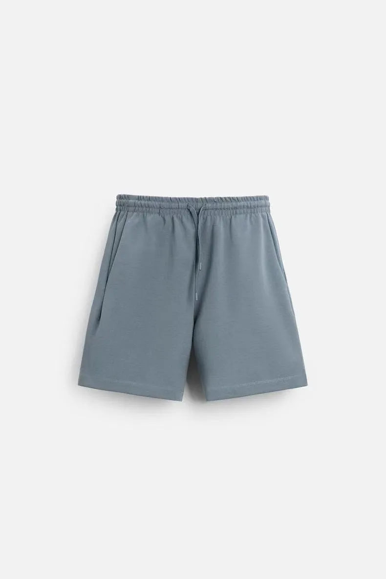 Man wearing a loose blue short sleeve top and matching shorts from a casual polyester co-ord set.