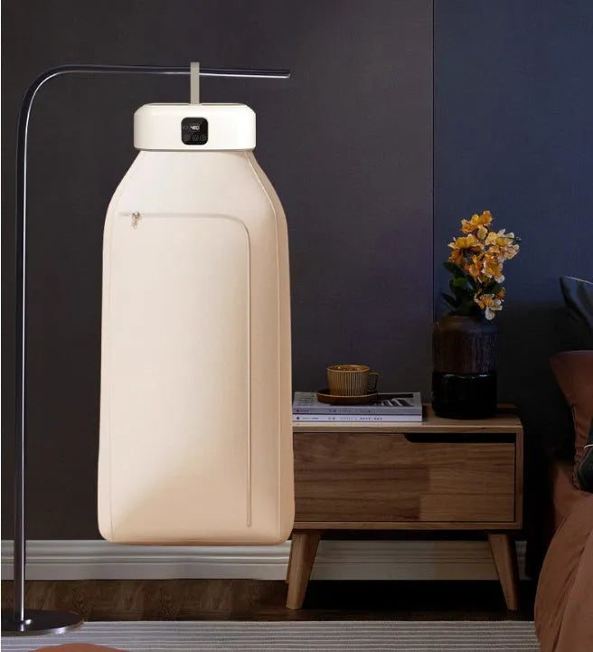 White foldable cylindrical laundry dryer with remote control on a table.