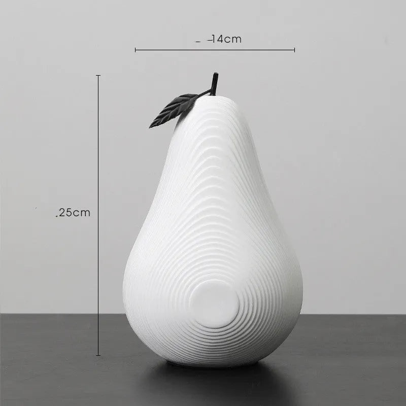 A black resin apple figurine and a white resin pear figurine on a wooden surface.