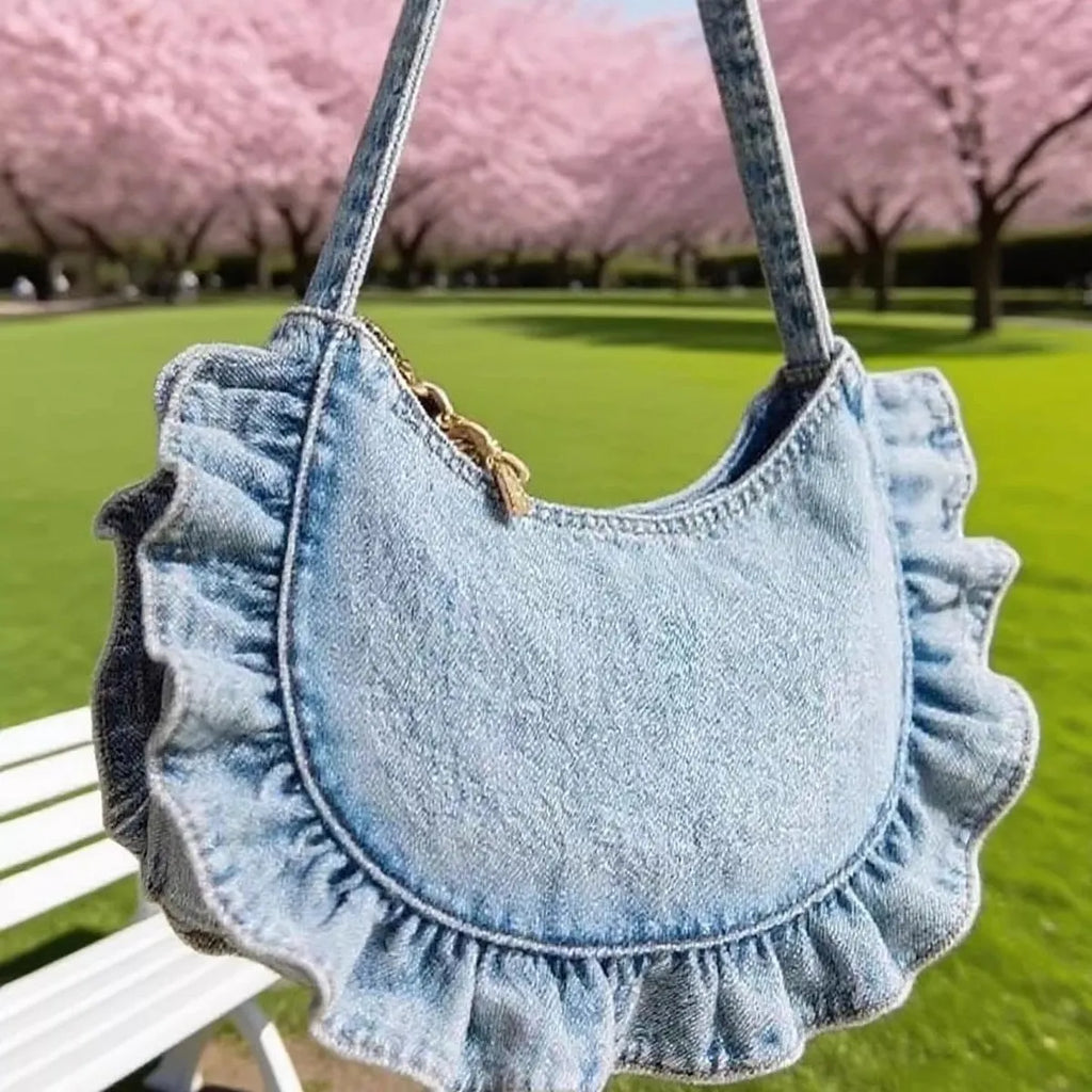 Denim blue cross-body bag with lace pleated trim and single shoulder strap, bucket shape.