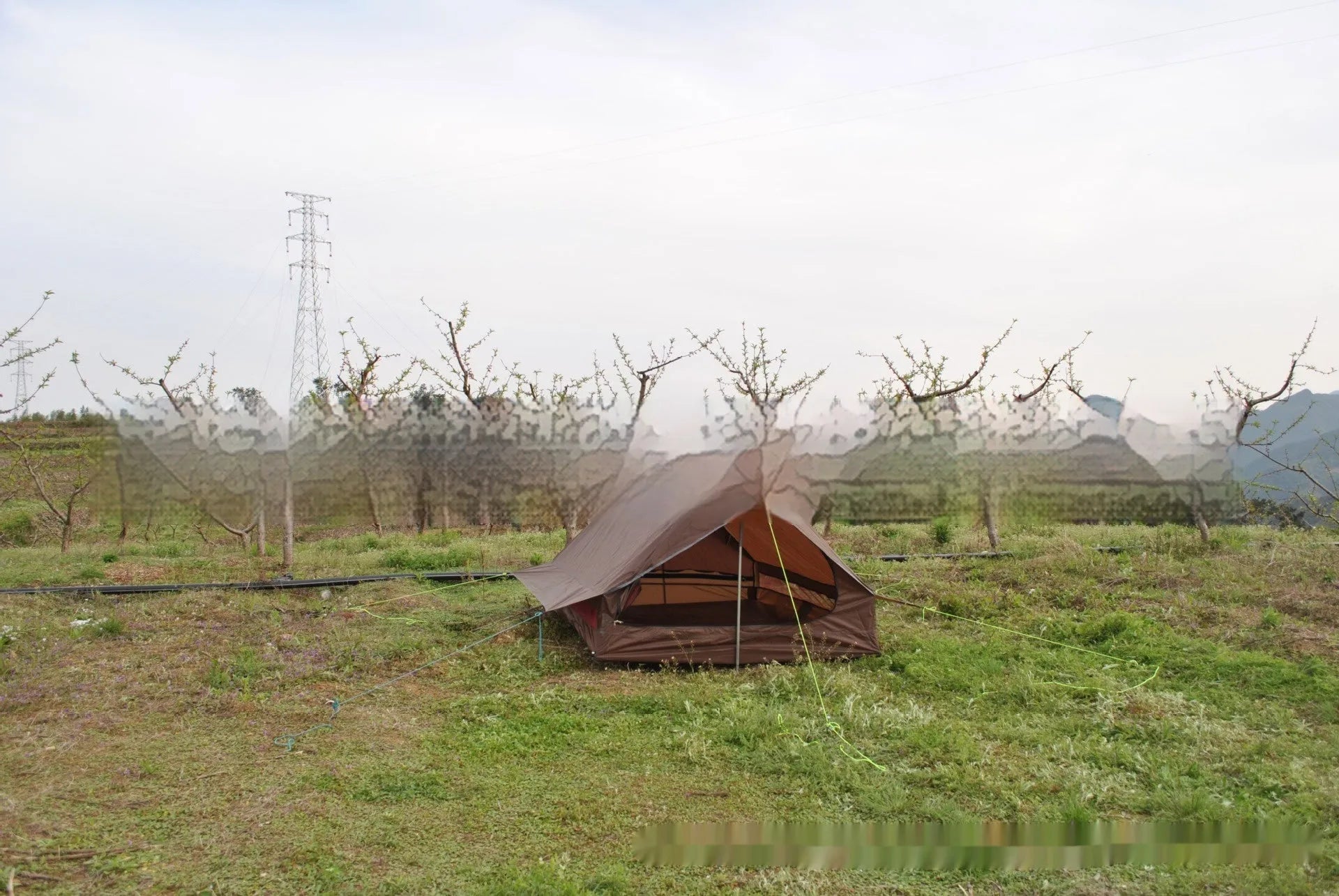 Brown A-line hiking tent pitched using trekking poles with guy ropes secured