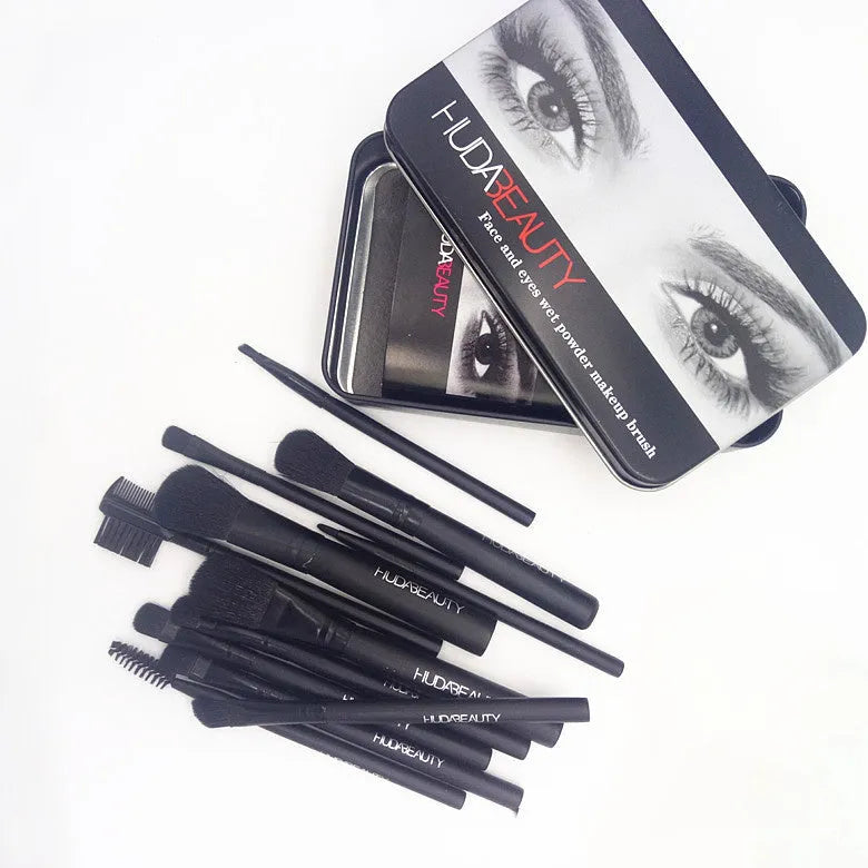 12 makeup brushes with corrugated silk nylon bristles and wooden handles in a black tin box on a flat surface.