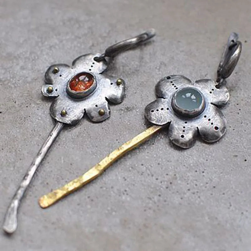 A pair of long, geometric flower-shaped drop earrings with an asymmetric two-tone metallic finish.