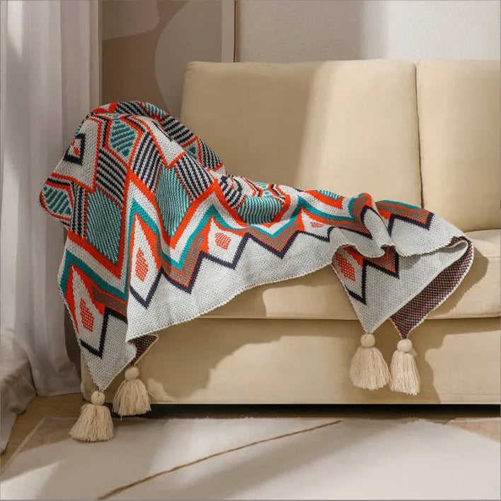 Bohemian style acrylic sofa cover blanket with tassel trim in a geometric pattern colour option.