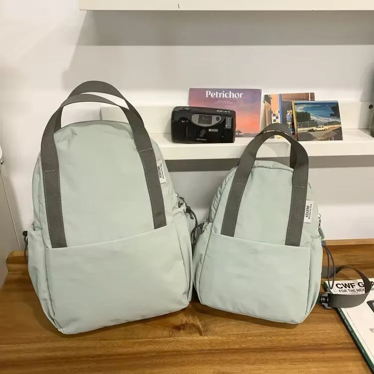 Simple solid colour nylon backpack with a curved shoulder strap and lock closure, shown in black.