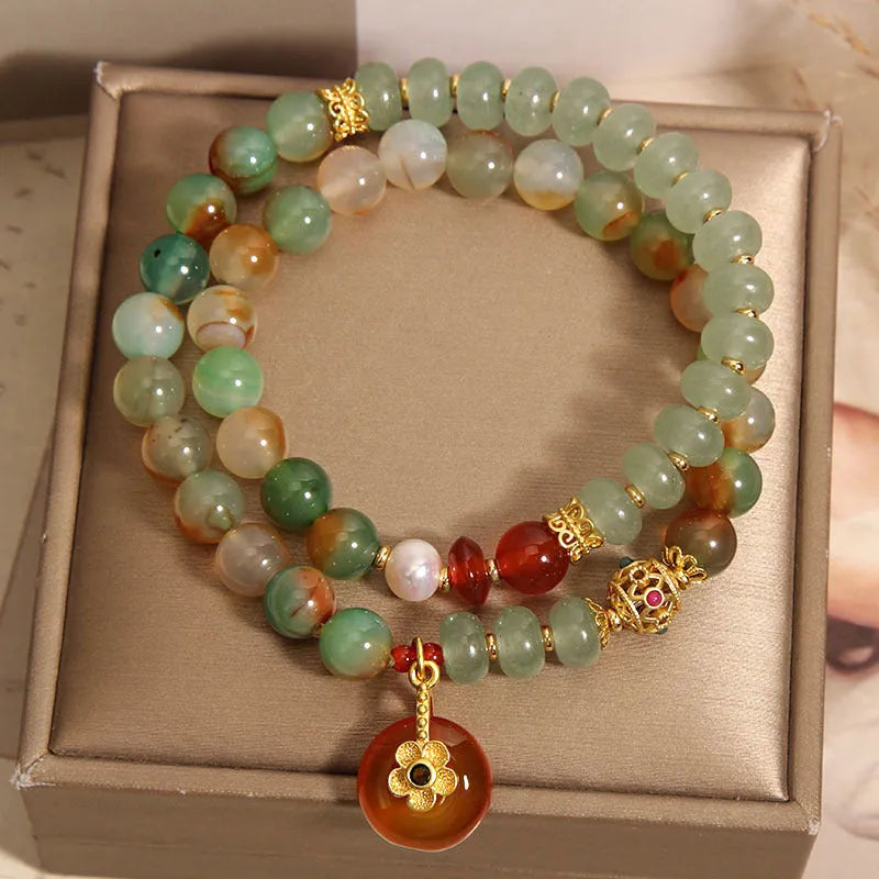 Women's peacock green agate double ring bracelet with safety buckle and rhinestones on a wrist.