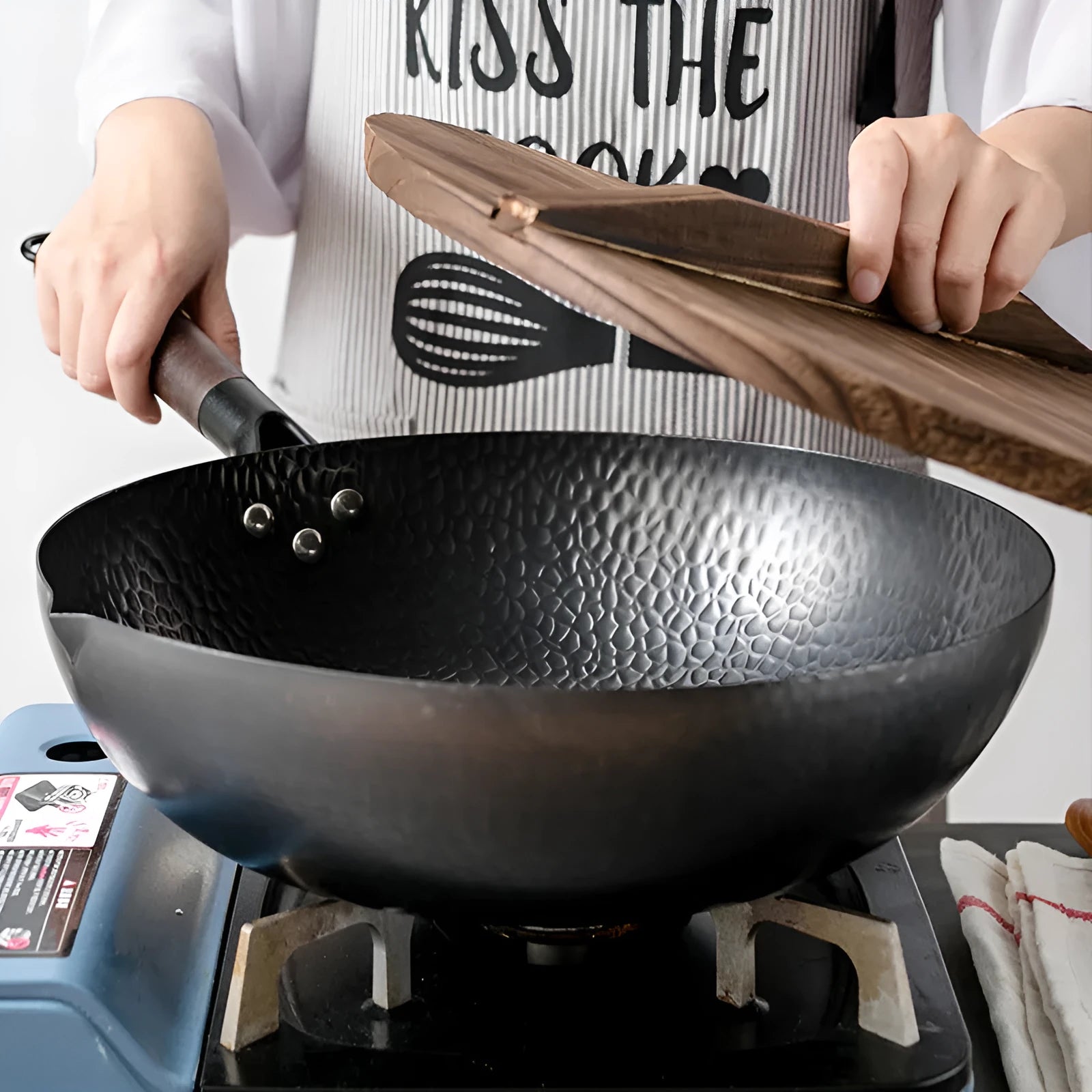 Handmade traditional black cast iron wok with wooden handle on a kitchen counter.