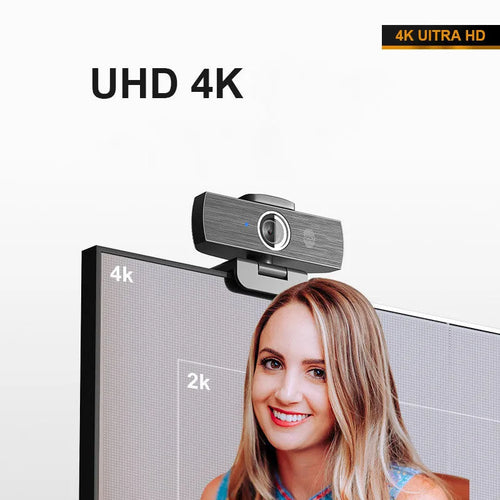 Black USB webcam with magnetic privacy cover on a desktop next to a laptop.