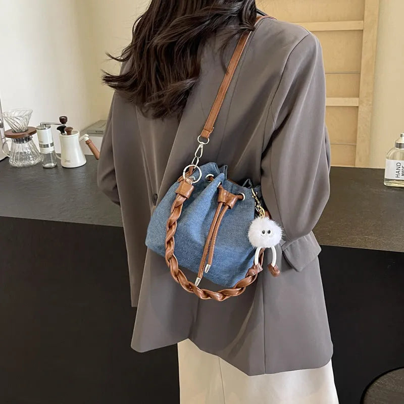 Blue one-shoulder cross body bucket bag with sandwich pocket design and messenger styling