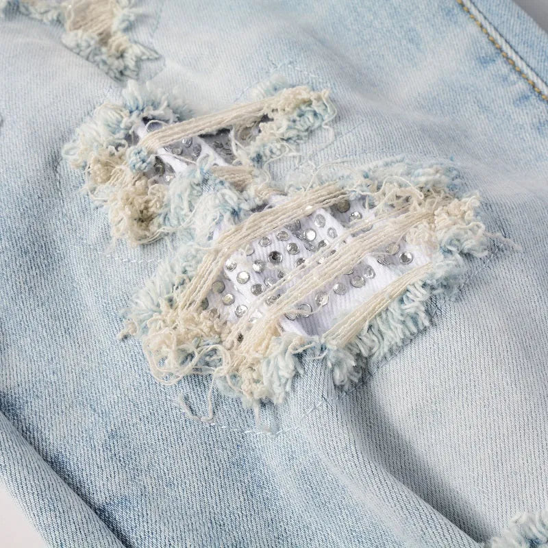 Light blue slim fit men's jeans with patch details, holes, and enzyme-washed finish