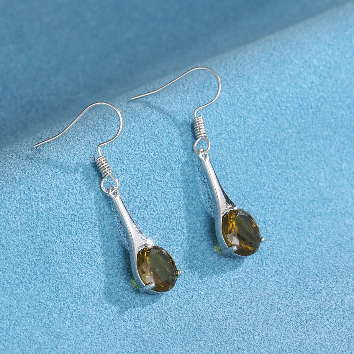 Olive green topaz coloured drop-shaped fashion earrings with a retro style on a white background.