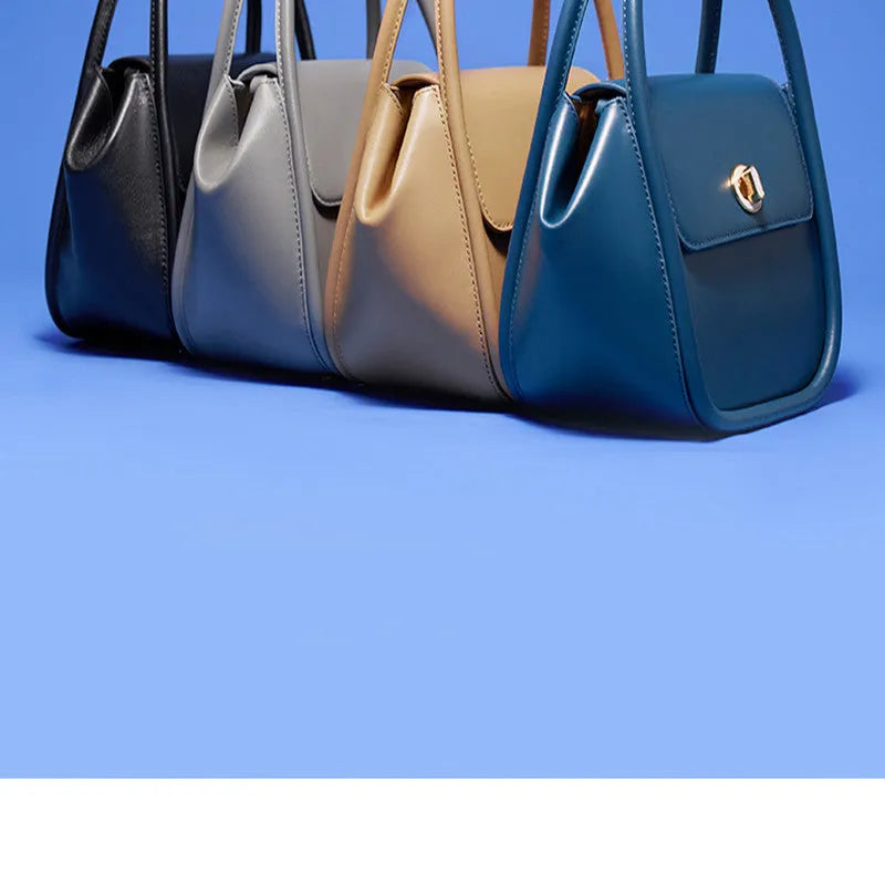 A women's leather wing-shaped tote bag with a metal latch, shown in blue on a cross-body strap.
