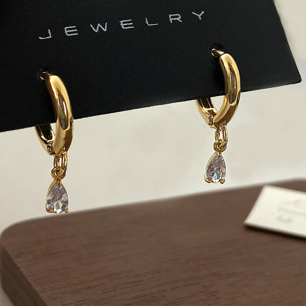 A zircon jewellery set comprising a geometric pendant necklace, stud earrings, and an anklet on a white background.
