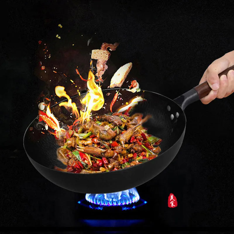 Handmade traditional black cast iron wok with wooden handle on a kitchen counter.