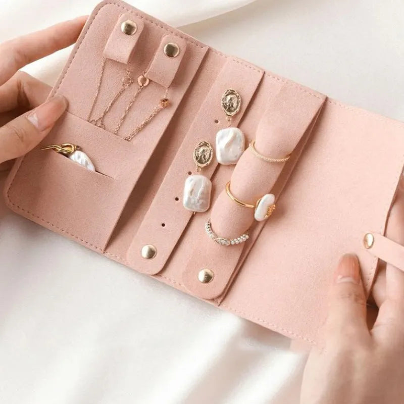 Brown PU leather jewellery storage pouch open to show microfiber lining, with earrings and a ring inside.