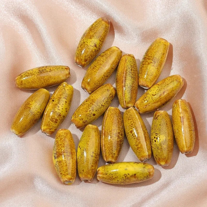 Assortment of ceramic bullet beads in pink, yellow, blue, red, coffee, green, orange, and mixed flower glaze colours.