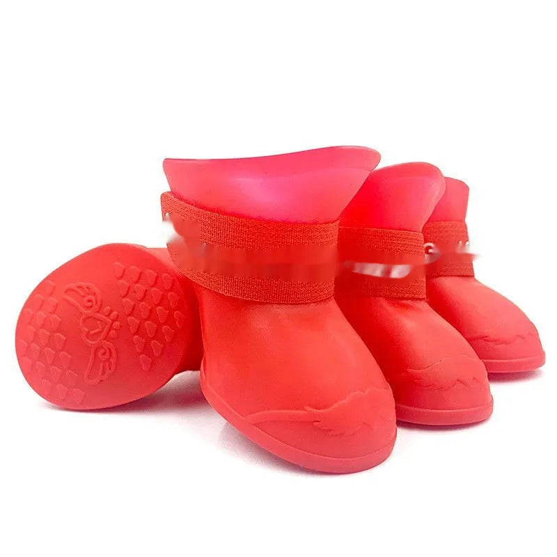 A set of four colourful rubber rain shoes for dogs, showing soft soles and bright pink, blue, orange, and red colours.