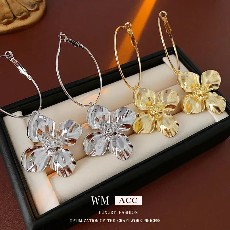 Close-up of silver needle floral geometric drop earrings in gold electroplated metal.