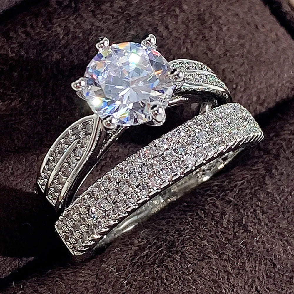 A white gold-coloured geometric bracelet ring with an integrated round element on a model's finger.
