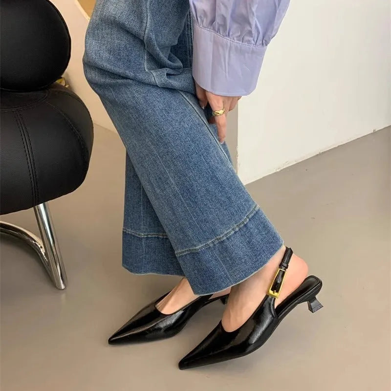 Women's black pointed toe leather strap shoes with a low rubber heel shown from the side.
