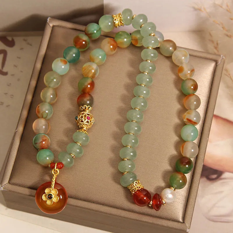 Women's peacock green agate double ring bracelet with safety buckle and rhinestones on a wrist.
