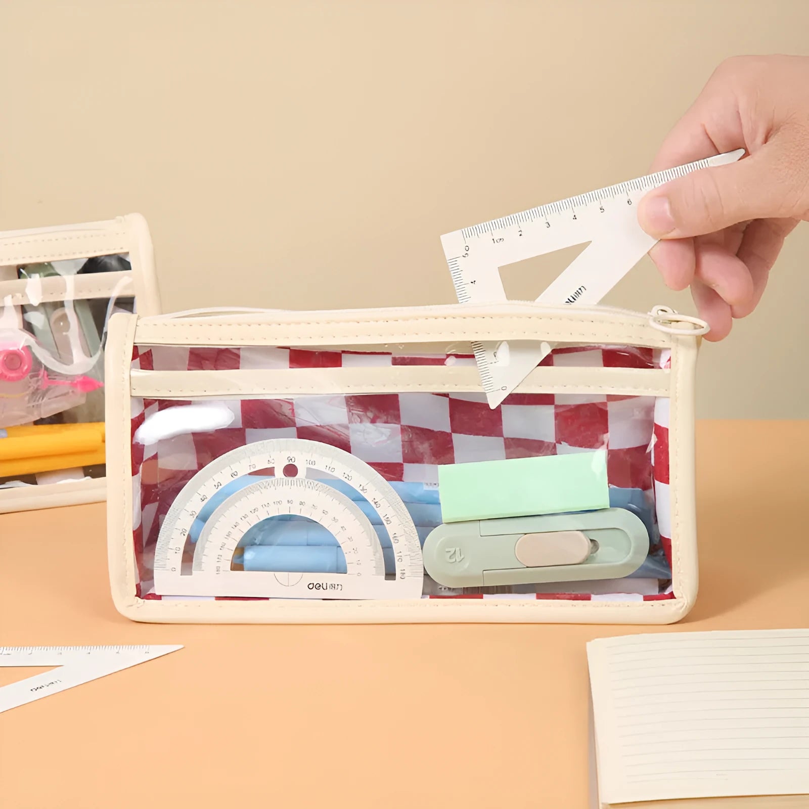 Transparent PVC pencil case with a chessboard grid pattern, showing pens inside, next to a red and white plaid version.