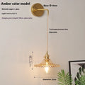 Brass wall lamp with an adjustable smoked grey glass lotus shade mounted beside a bed.