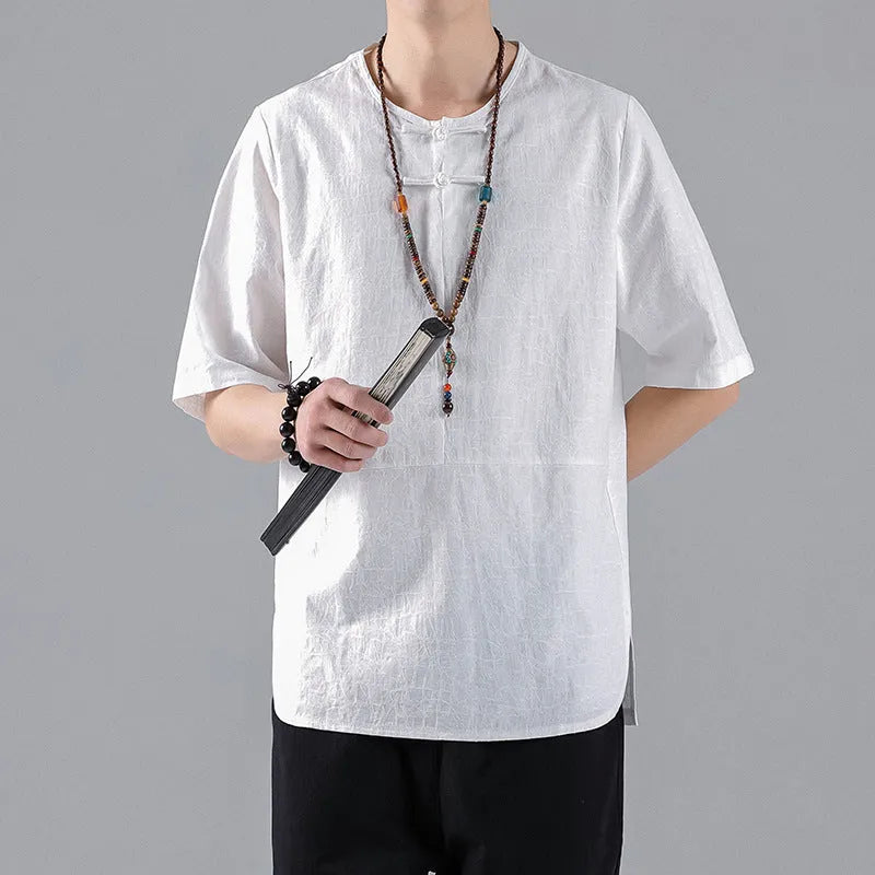 Man wearing a black loose-fit linen t-shirt with a retro jacquard pattern and fastener decoration.