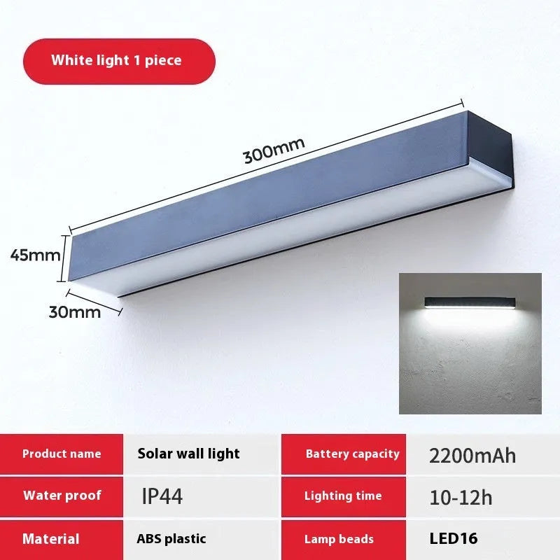 Black solar-powered outdoor wall lamp with integrated solar panel, mounted on a garden wall.