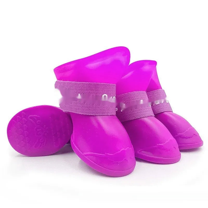 A set of four colourful rubber rain shoes for dogs, showing soft soles and bright pink, blue, orange, and red colours.