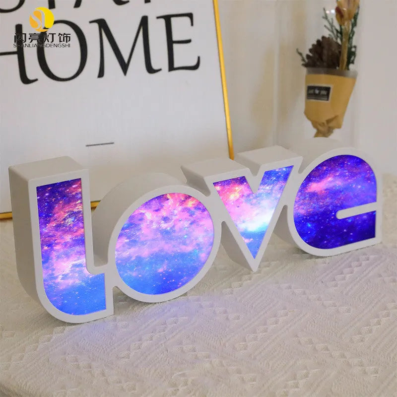 LED LOVE light with rainbow-coloured plastic lampshade on a desk
