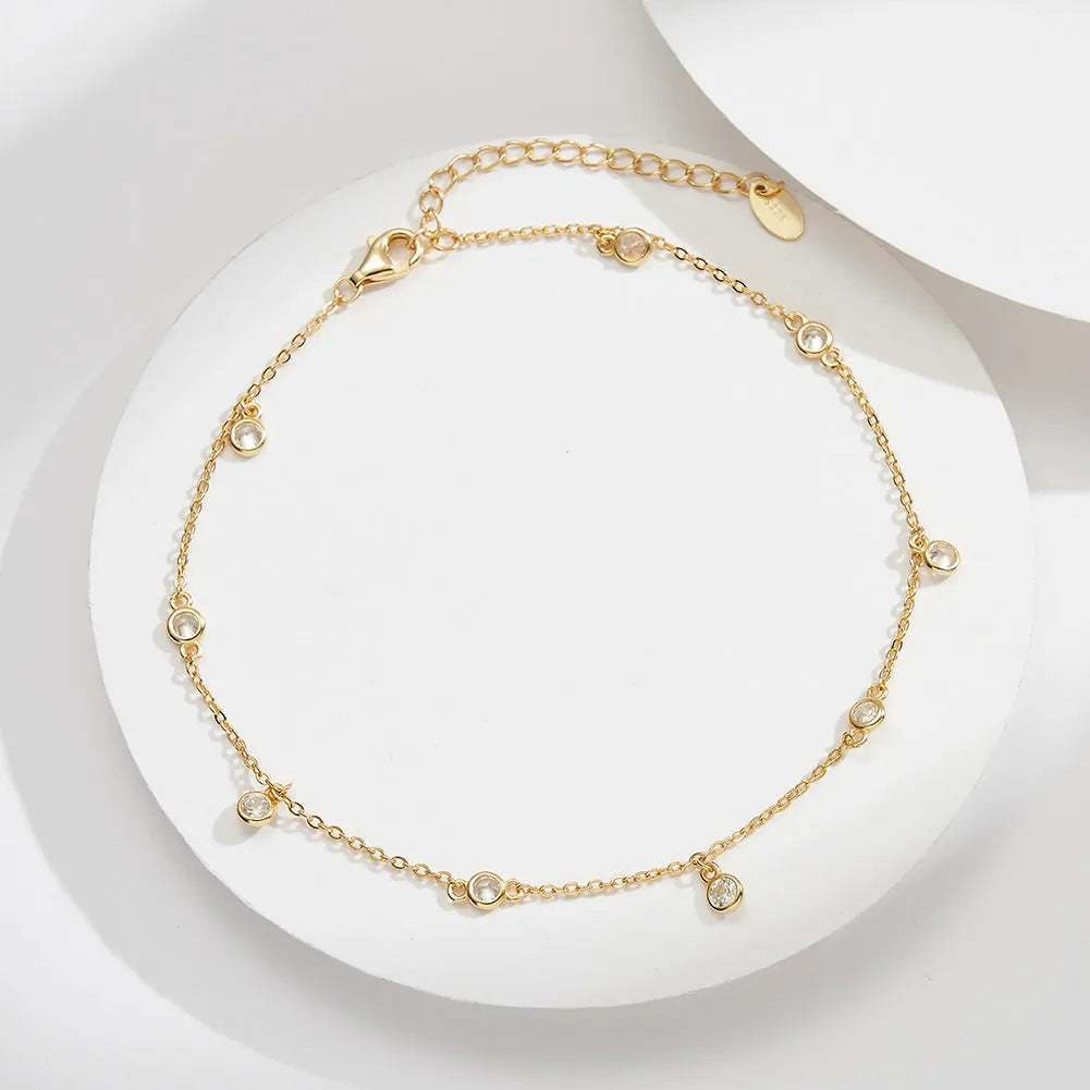 Close-up of a women's geometric zirconium pendant anklet on a sterling silver chain.