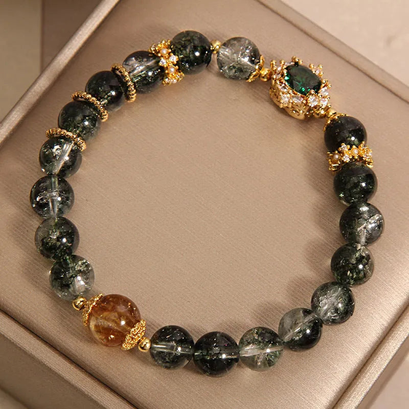 Gold electroplated women's bracelet with a green phantom quartz stone, ruby accents, rhinestones, and pearls.