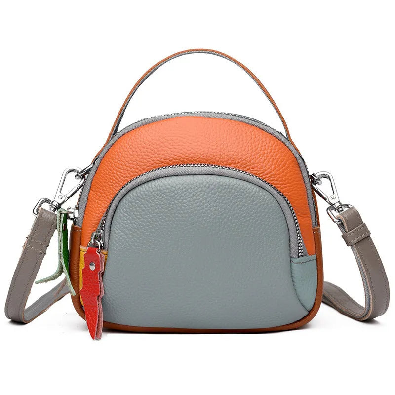 Round hand-held crossbody bag made from first layer cowhide leather with visible sewing line detail on exterior