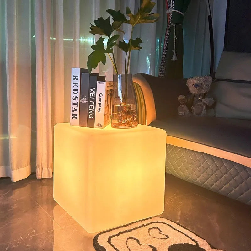 A modern square white LED cube light functioning as a waterproof stool for outdoor gardens.