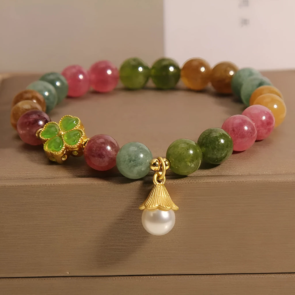 Natural colour tourmaline bracelet with four-leaf clover charm and pearl pendant on wrist