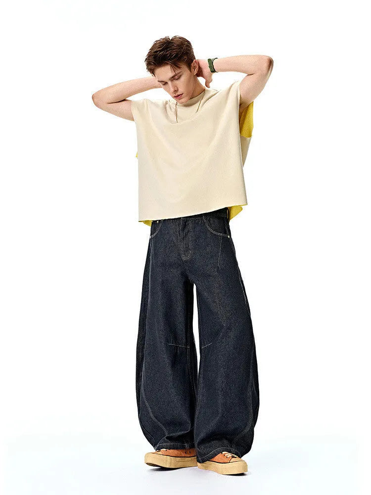 Men's wide leg denim trousers in original cow colour, laid flat to show mid-waist and relaxed fit.
