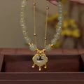 Green women's bracelet with safety lock and bell pendant in drop shape design