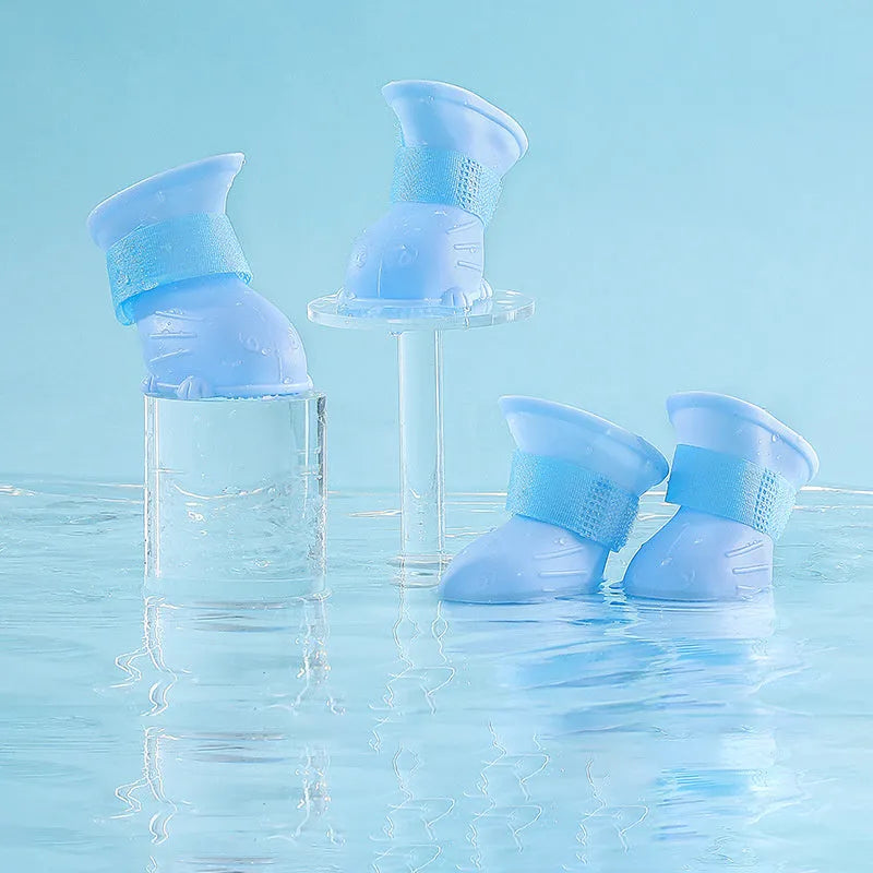 Four waterproof silicone dog rain boots in blue, grey, light blue and pink on a white background