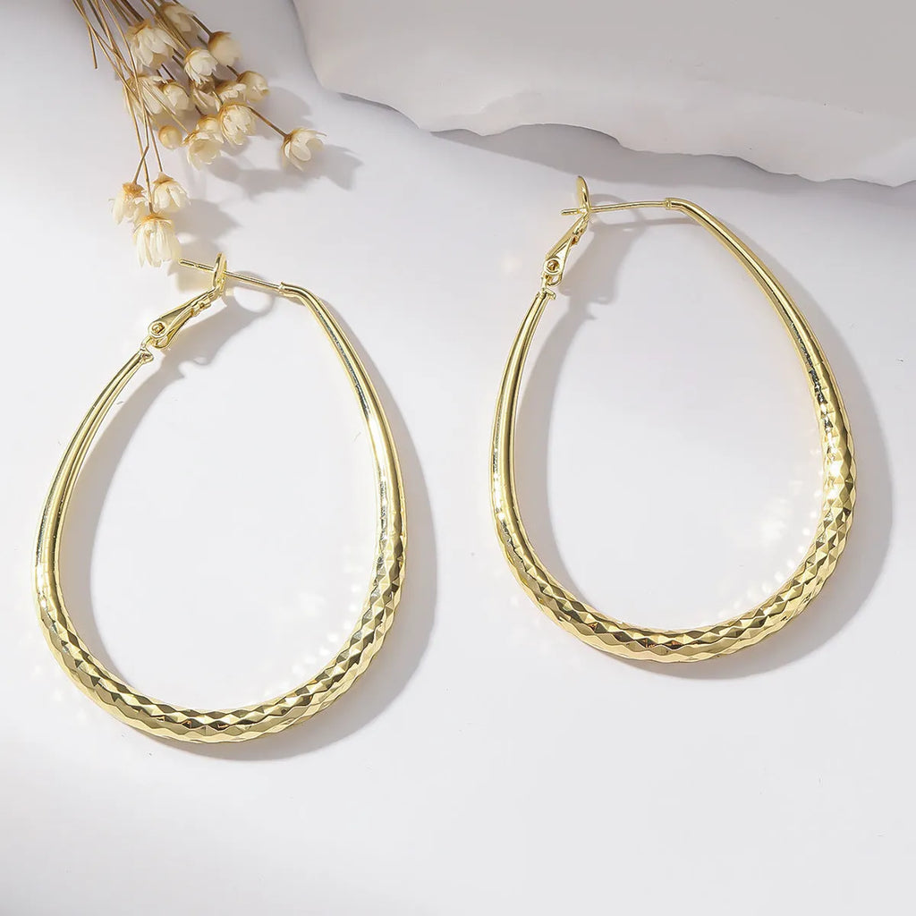 Gold glossy egg-shaped spring fastener earrings made from hypoallergenic copper, unisex geometric design