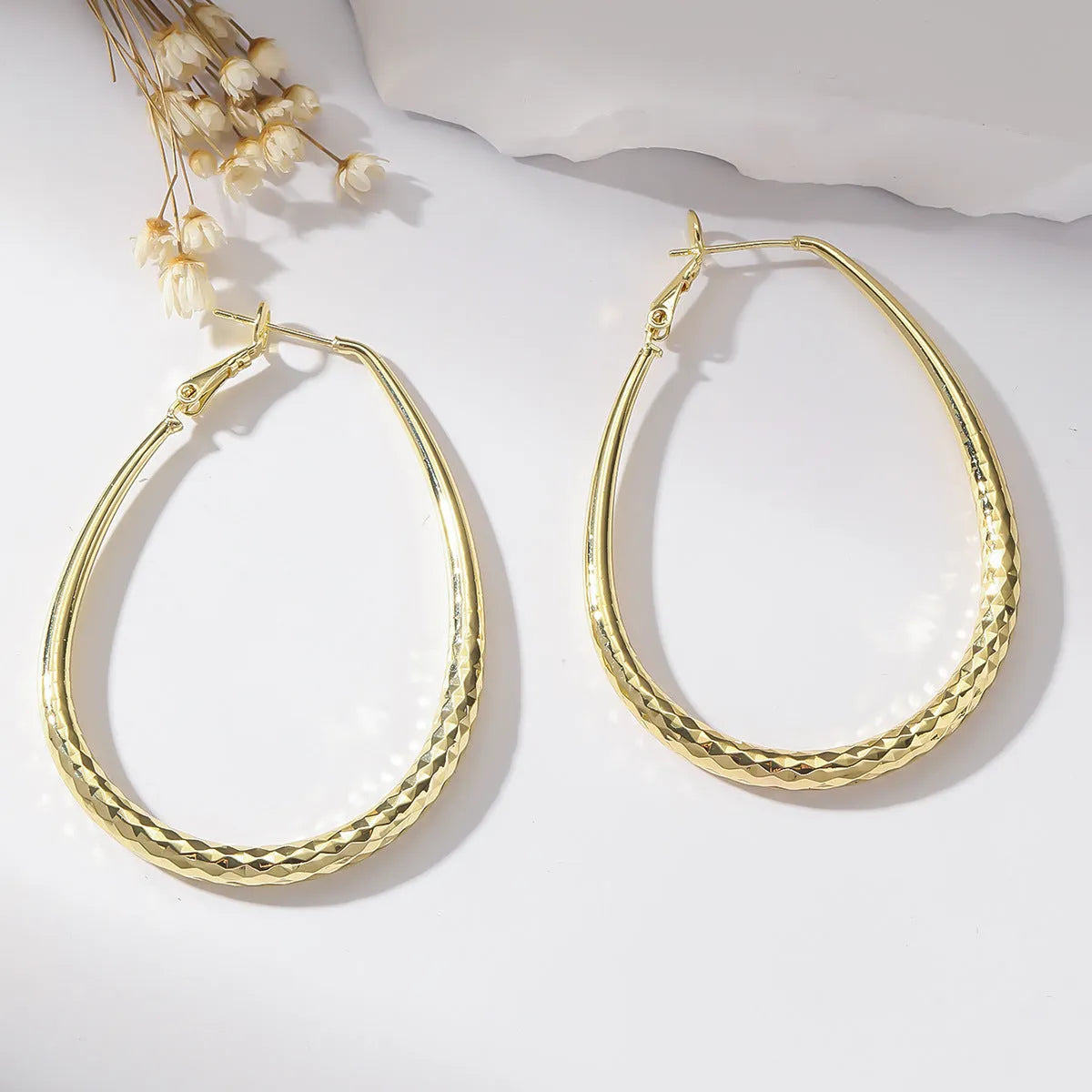 Gold glossy egg-shaped spring fastener earrings made from hypoallergenic copper, unisex geometric design