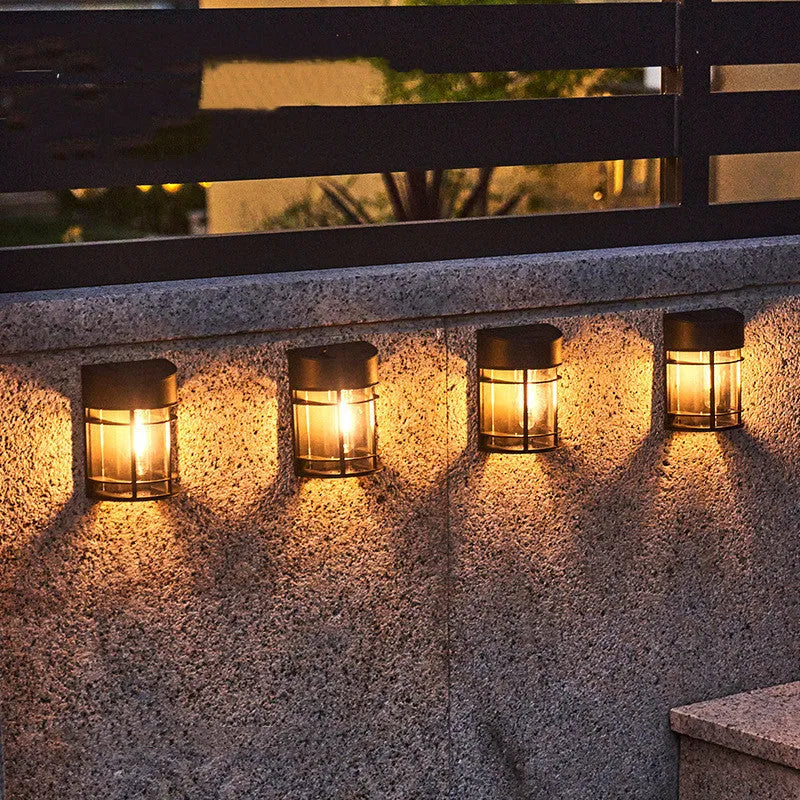 Solar-powered outdoor wall light with warm white LED, mounted on a garden wall.